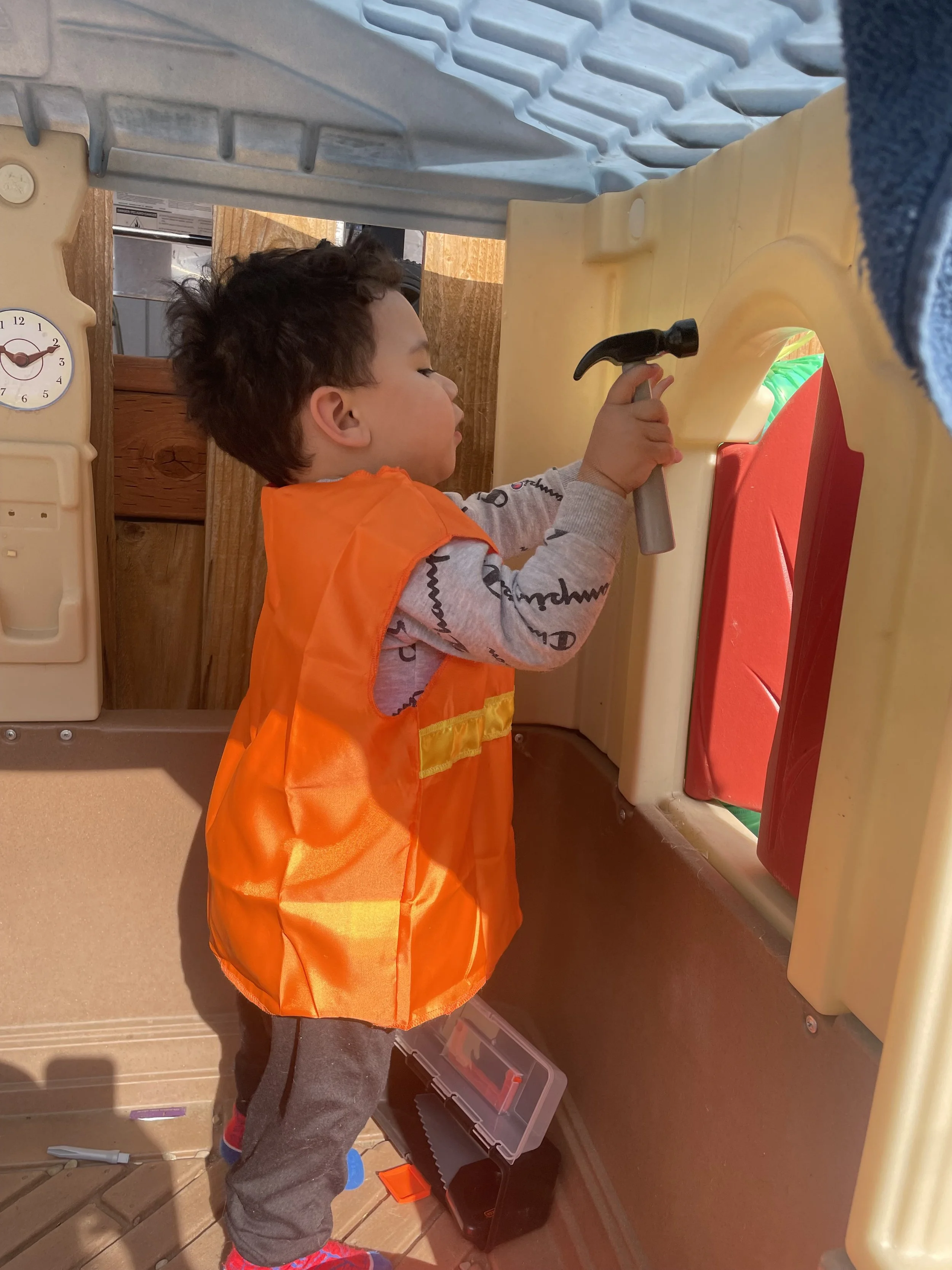 Child in a safety vest with a toy hammer
